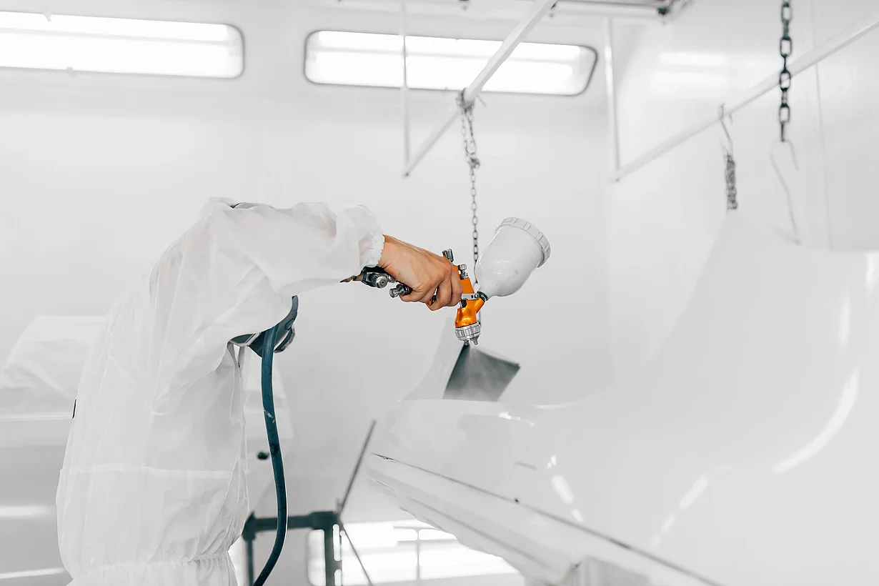 A person is painting a car as an example of the use of CO₂-based raw materials in coatings and paints.