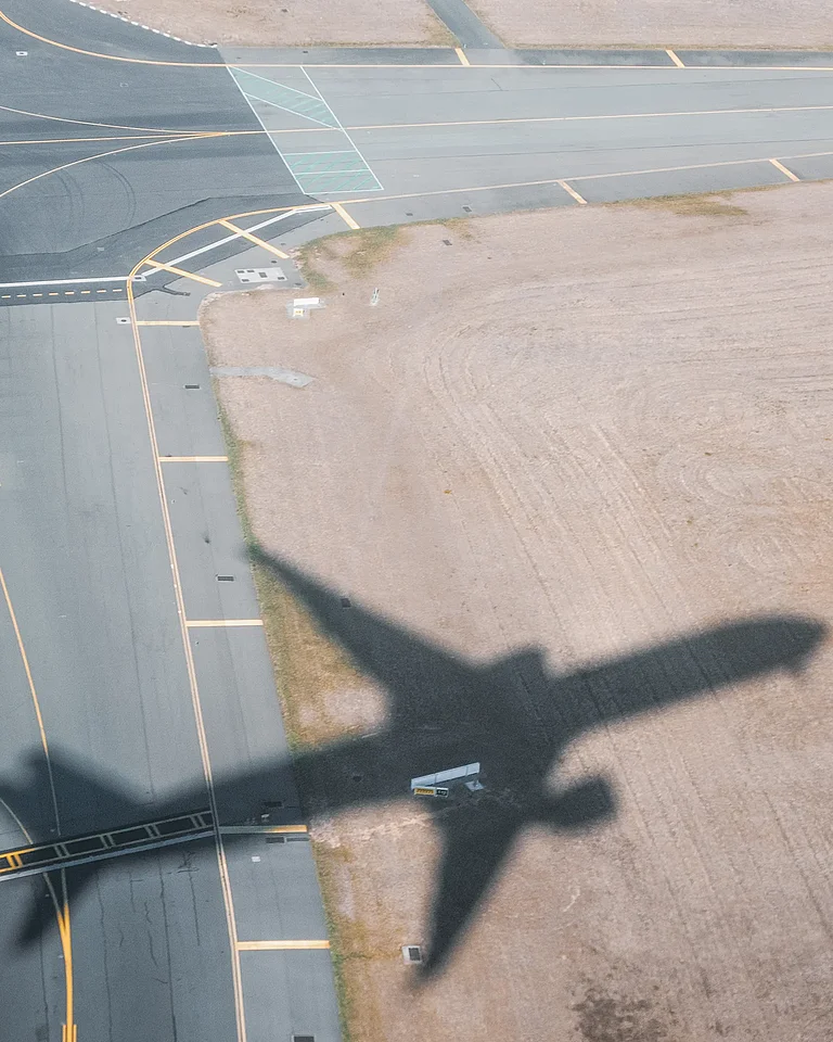 Schatten eines abhebenden Flugzeugs auf dem Boden eines Flughafens.