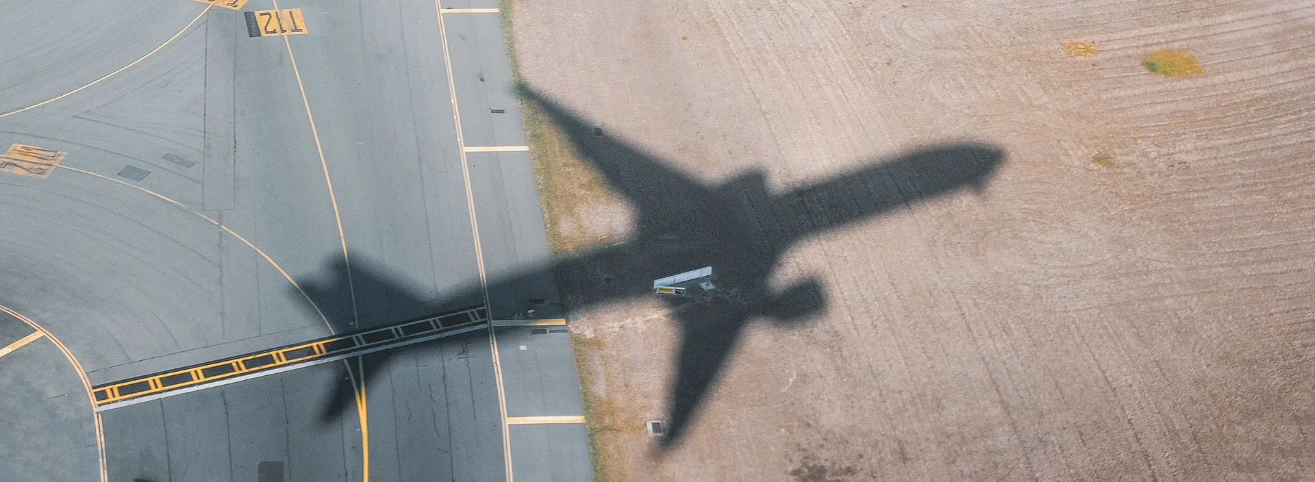 Schatten eines abhebenden Flugzeugs auf dem Boden eines Flughafens.